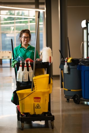 Smiling Stathakis day porter pushing cleaning station in facility