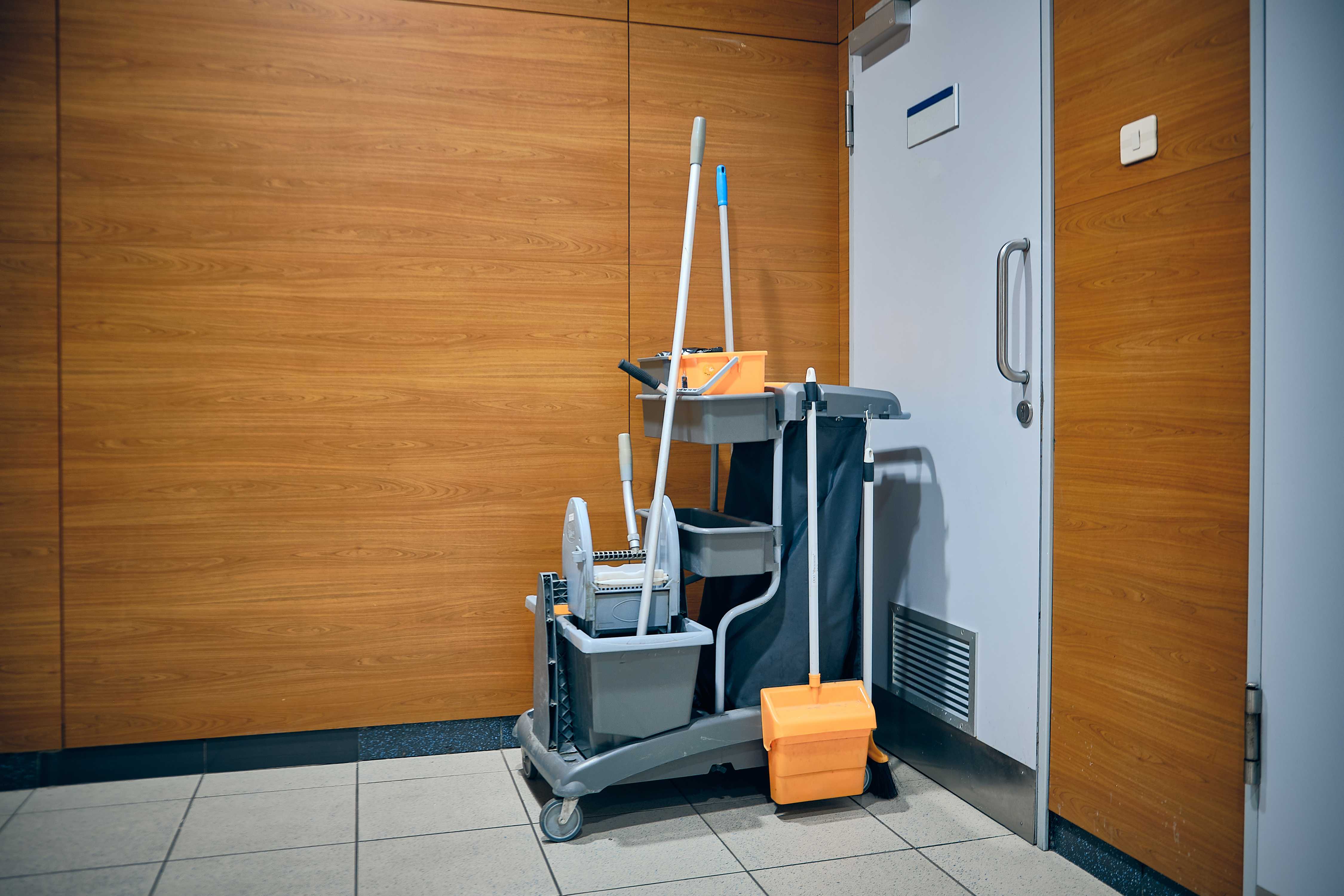 Cleaning tools on a cart next to a door inside a facility