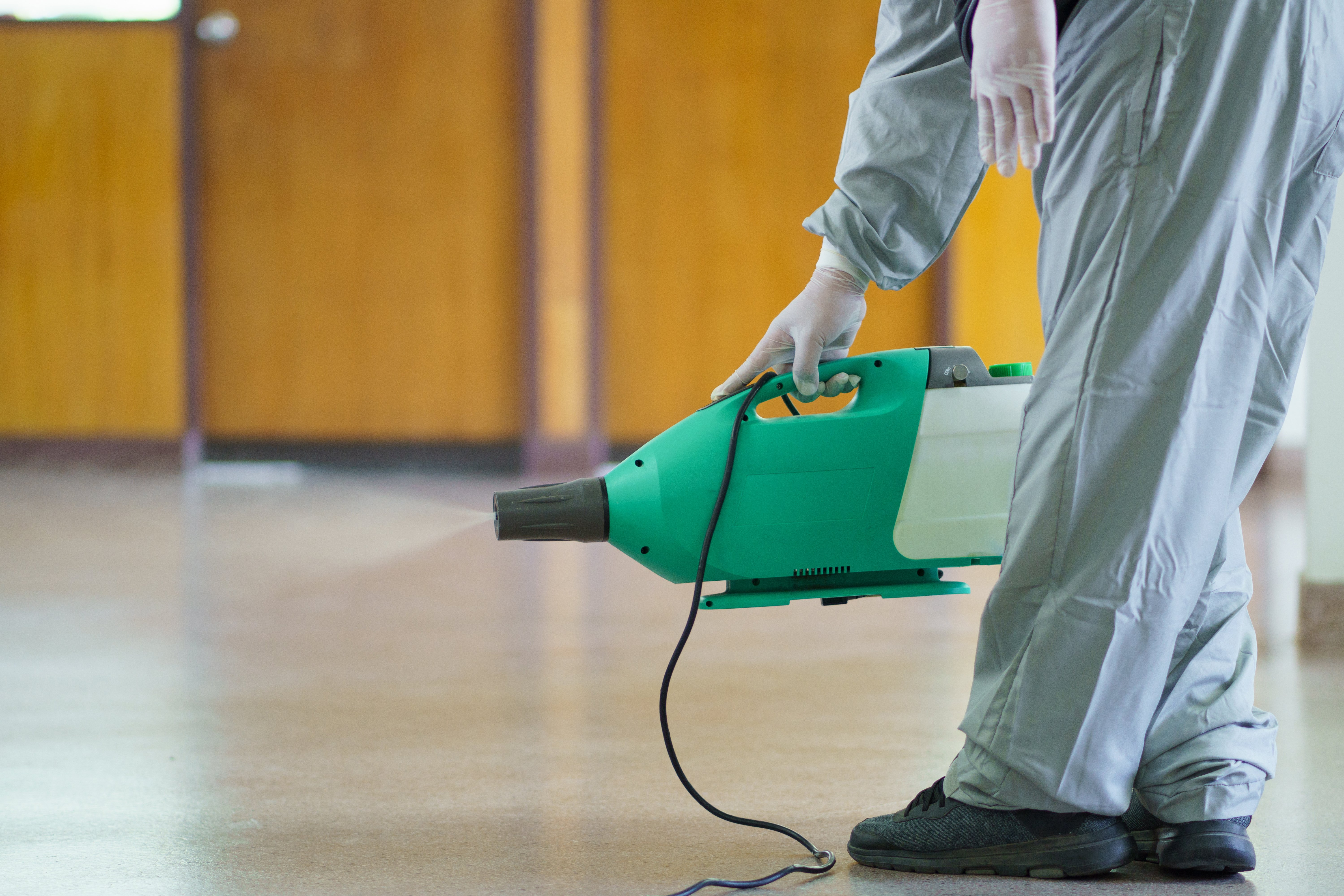 Disinfectant team cleaner using a fog machine to clean hallway