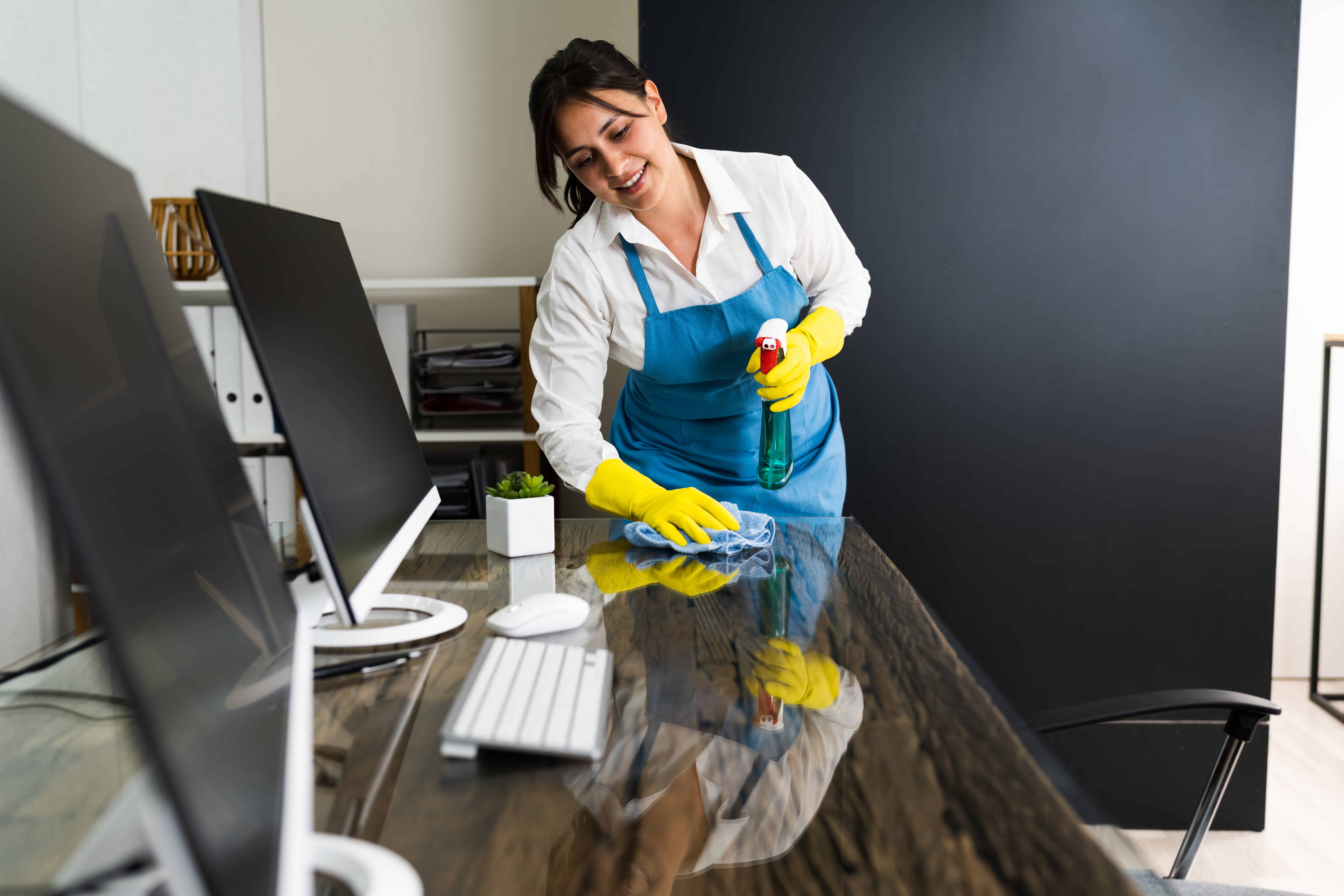 Professional cleaning company wiping down and sanitizing office desks