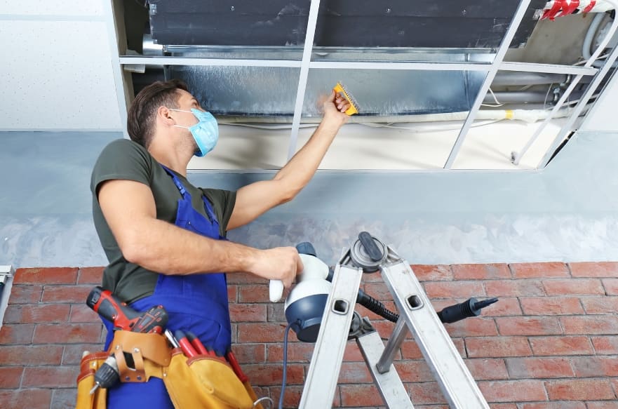 male cleaner, cleaning industrial air conditioning unit 